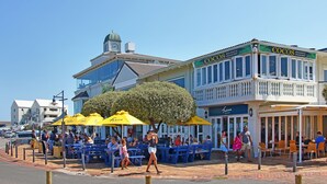 Un restaurante frente al mar con terraza y una torre del reloj al fondo.