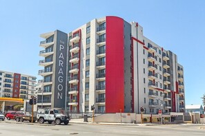 Un edificio de varios pisos con balcones, una llamativa banda vertical roja y el nombre "The Paragon" en su fachada.