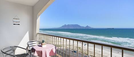 A balcony with a view of the ocean and a mountain.