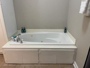 Ein Badezimmer mit einer weißen Badewanne, zwei Wasserhähnen und zwei Seifenflaschen auf dem Waschtisch.
