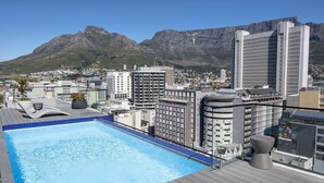 Ein Pool auf dem Dach mit Stadtansicht und Bergen im Hintergrund.