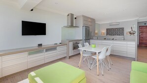 Een moderne keuken met witte kasten, een inbouwoven en een grote koelkast.