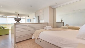 Een moderne slaapkamer met een groot bed, een inbouwkleedkast en uitzicht op de zee.