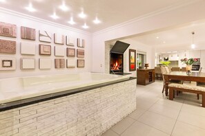 A modern living room with a fireplace, a dining area, and a wall with framed artwork.