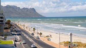 Una carretera costera con una playa y montañas al fondo.