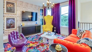 A living room with a brick wall, a yellow armchair, a red sofa, and a colorful rug. - The Ultimate Hip-Hop Haven – Rooftop Patio (Nashville)