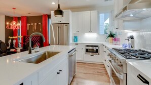 A modern kitchen with white cabinetry, stainless steel appliances, and a central island. - The Ultimate Hip-Hop Haven – Rooftop Patio (Nashville)