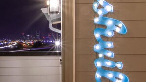 A neon sign spelling "Waverly" on a wall, with a cityscape view in the background. - The Ultimate Hip-Hop Haven – Rooftop Patio (Nashville)