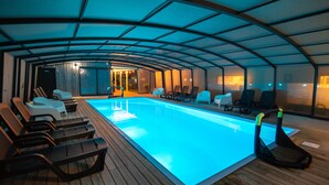 An indoor swimming pool with lounge chairs and a wooden deck. - Domki Fantazja Dębki (Krokowa)