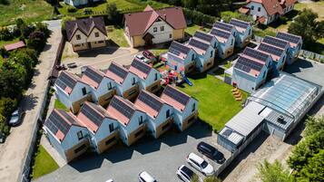 A residential area with multiple houses, some with solar panels, a playground, and a greenhouse.