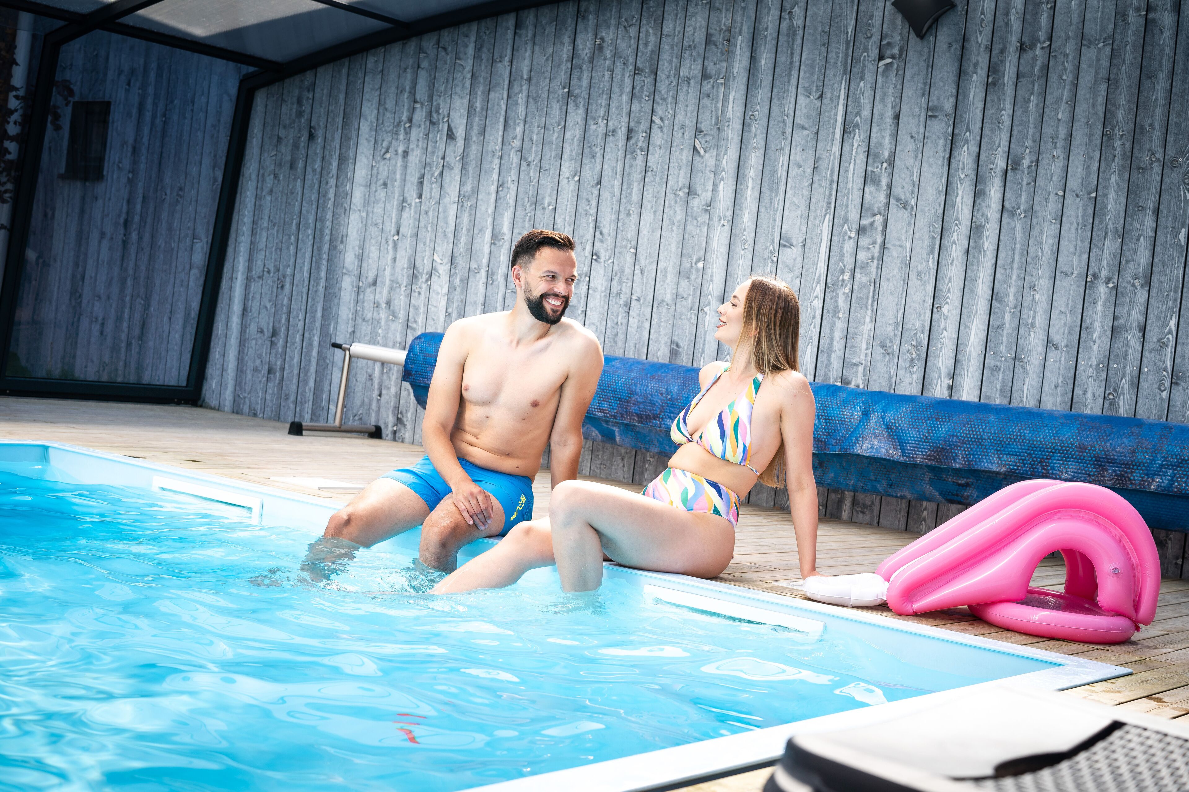 Una piscina con muelle de madera y un flotador inflable azul.