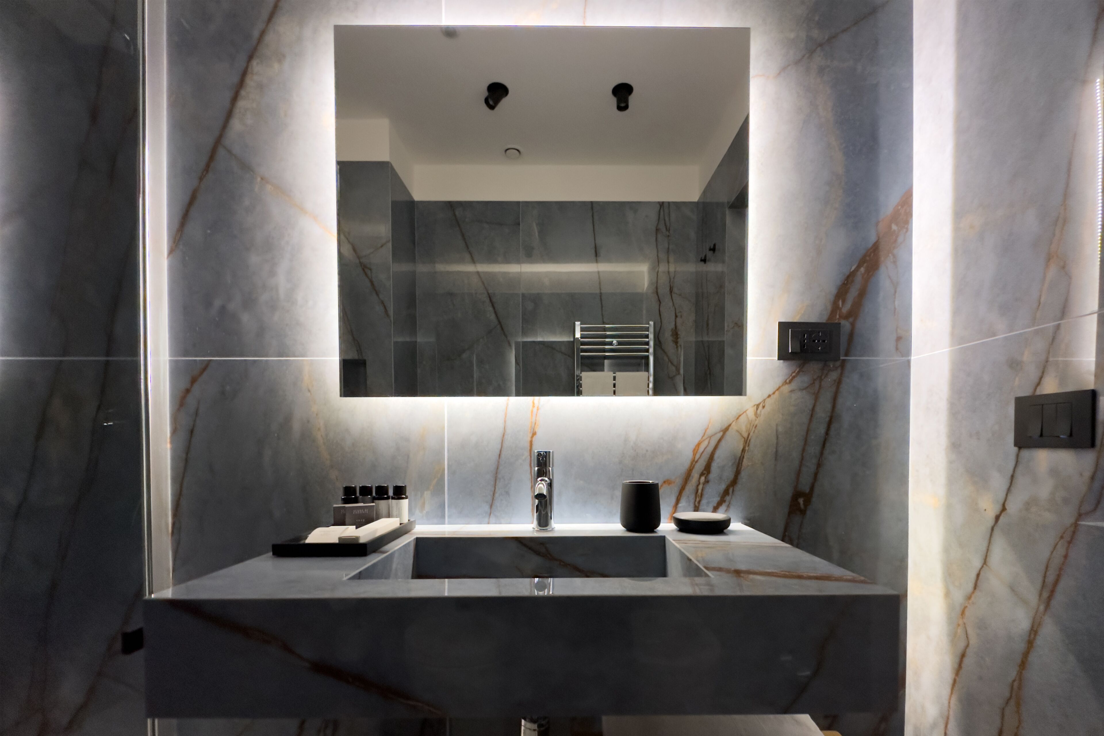 A modern bathroom with a large mirror, a sink, and a towel rack.