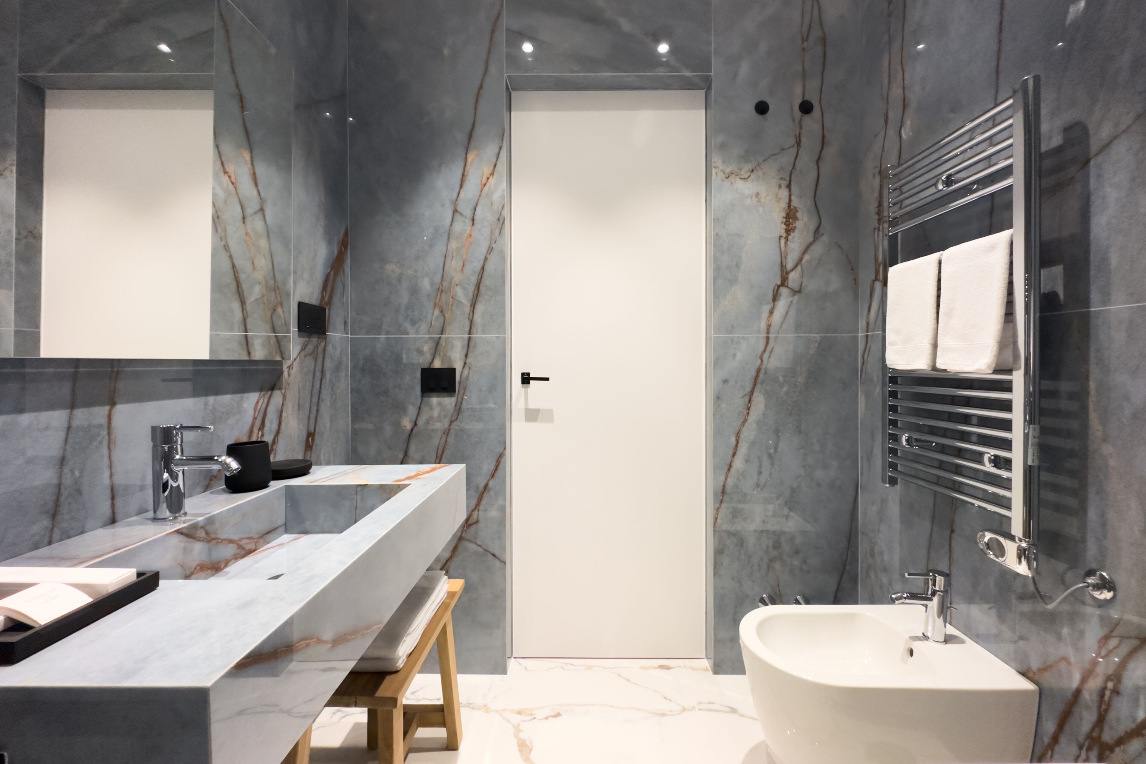 A modern bathroom with a marble vanity, a freestanding bathtub, and a large mirror.