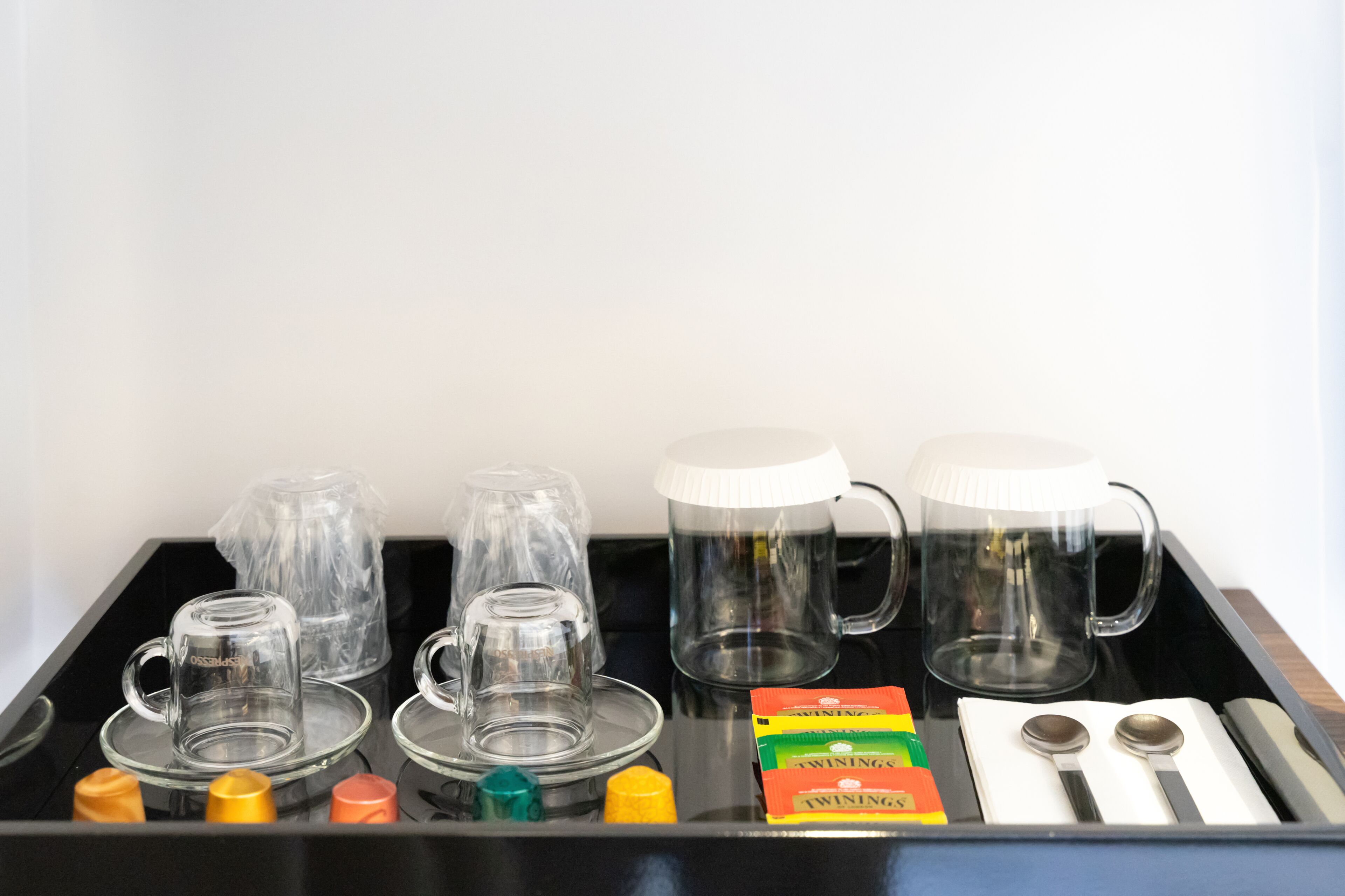 A tray with glass mugs, a coffee pot, and Twinings tea boxes.