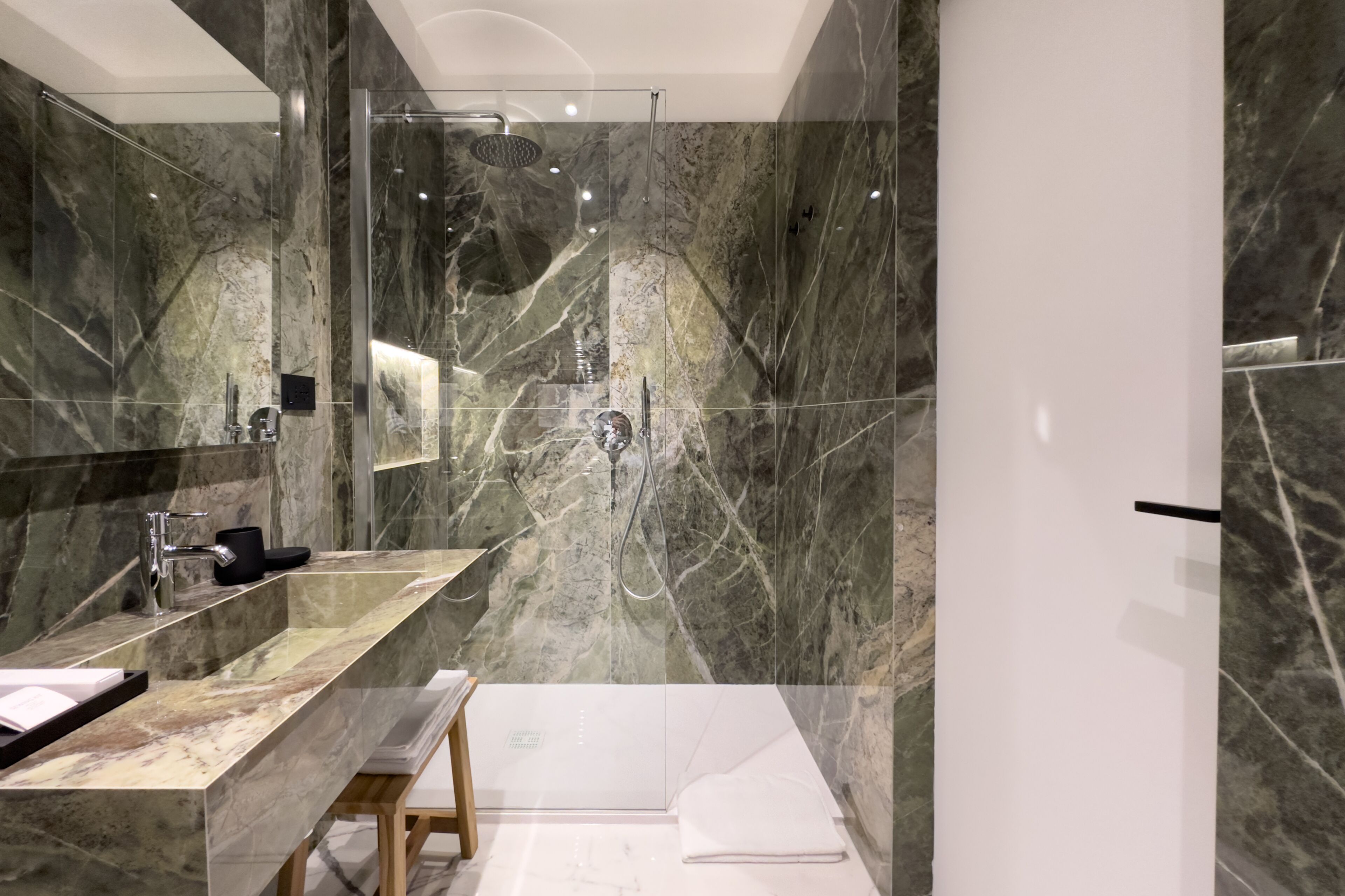 Ein modernes Badezimmer mit Marmor-Waschtisch, einer Duschkabine aus Glas und einer weißen Badewanne.