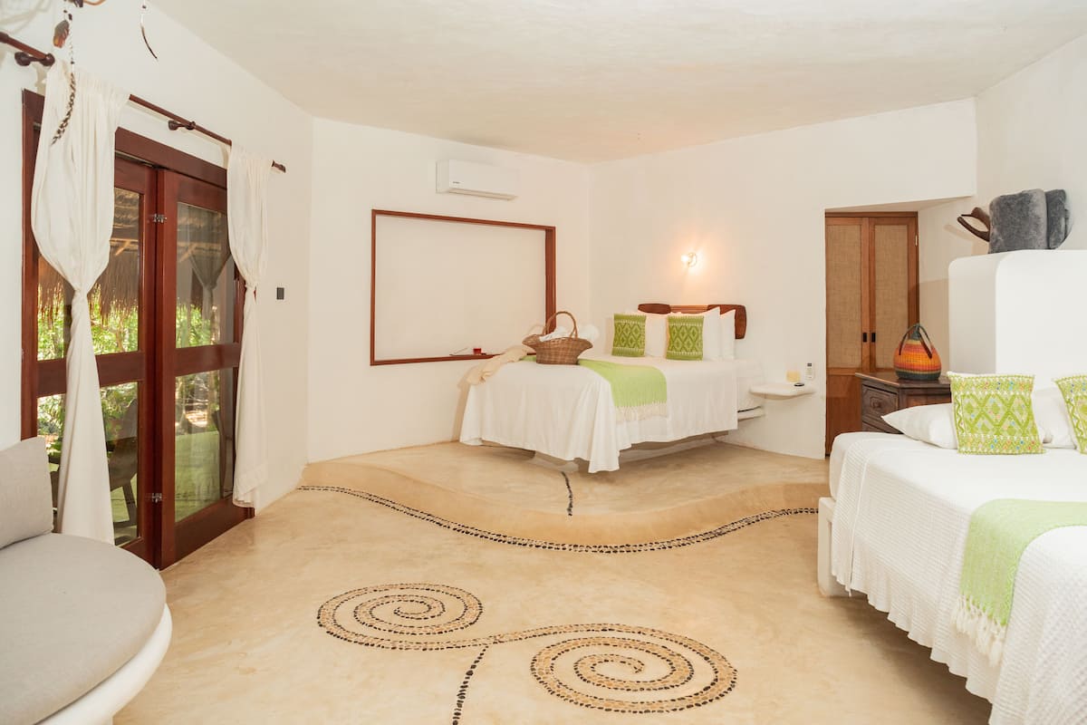 A bedroom with a bed, a bedside table, a lamp, and a window with curtains.