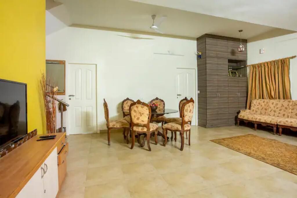 A living room with a dining table and chairs, a sofa, a TV, and a ceiling fan.