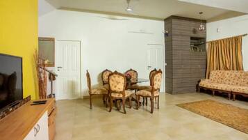 A living room with a dining table and chairs, a sofa, a TV, and a ceiling fan.