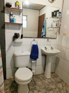 Ein Badezimmer mit Toilette, Waschbecken und Ablagen für Toilettenartikel.