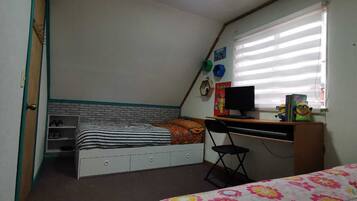 Un dormitorio con una cama, un escritorio, una silla, una ventana con persianas y un estante con zapatos.