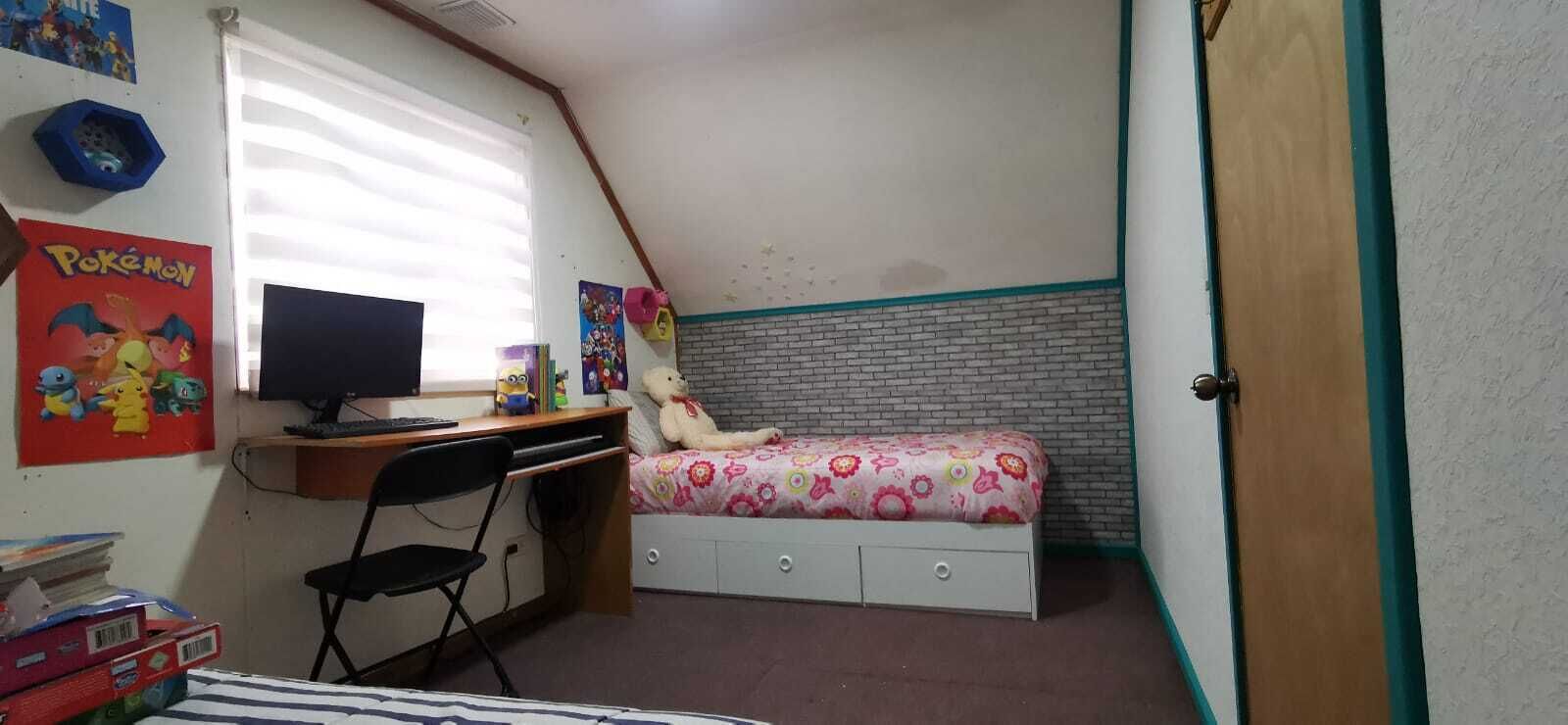 A bedroom with a desk, chair, bed, and a window.