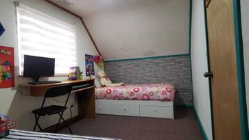 A bedroom with a desk, chair, bed, and a window.