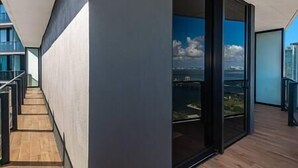 Un intérieur moderne avec un plancher en bois et une porte vitrée donnant sur un balcon avec vue sur la ville.
