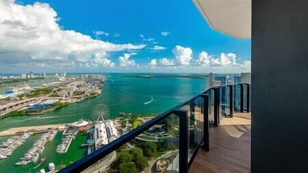 Un immeuble de grande hauteur doté d’un balcon donnant sur une marina et sur une grande roue.