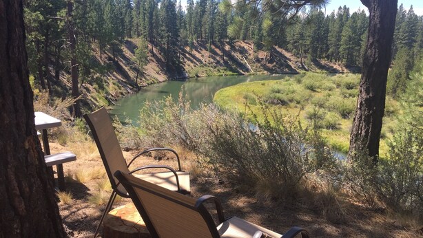 A bench overlooking a river with a forested hillside in the background. - Quiet apt-cabin on Deschutes River (Bend)