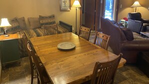 A dining area with a wooden table and chairs, a sofa, and a lamp. - Quiet apt-cabin on Deschutes River (Bend)