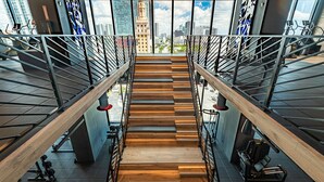 A staircase with a wooden finish, metal railings, and gym equipment on either side.