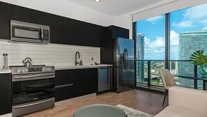 A modern kitchen with a large window, a refrigerator, and a microwave. - Breathtaking Lux Studio in Downtown #3107 (Miami)
