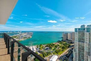 Un immeuble de grande hauteur offrant une vue sur un paysage urbain côtier, comprenant une étendue d’eau et une grande roue.