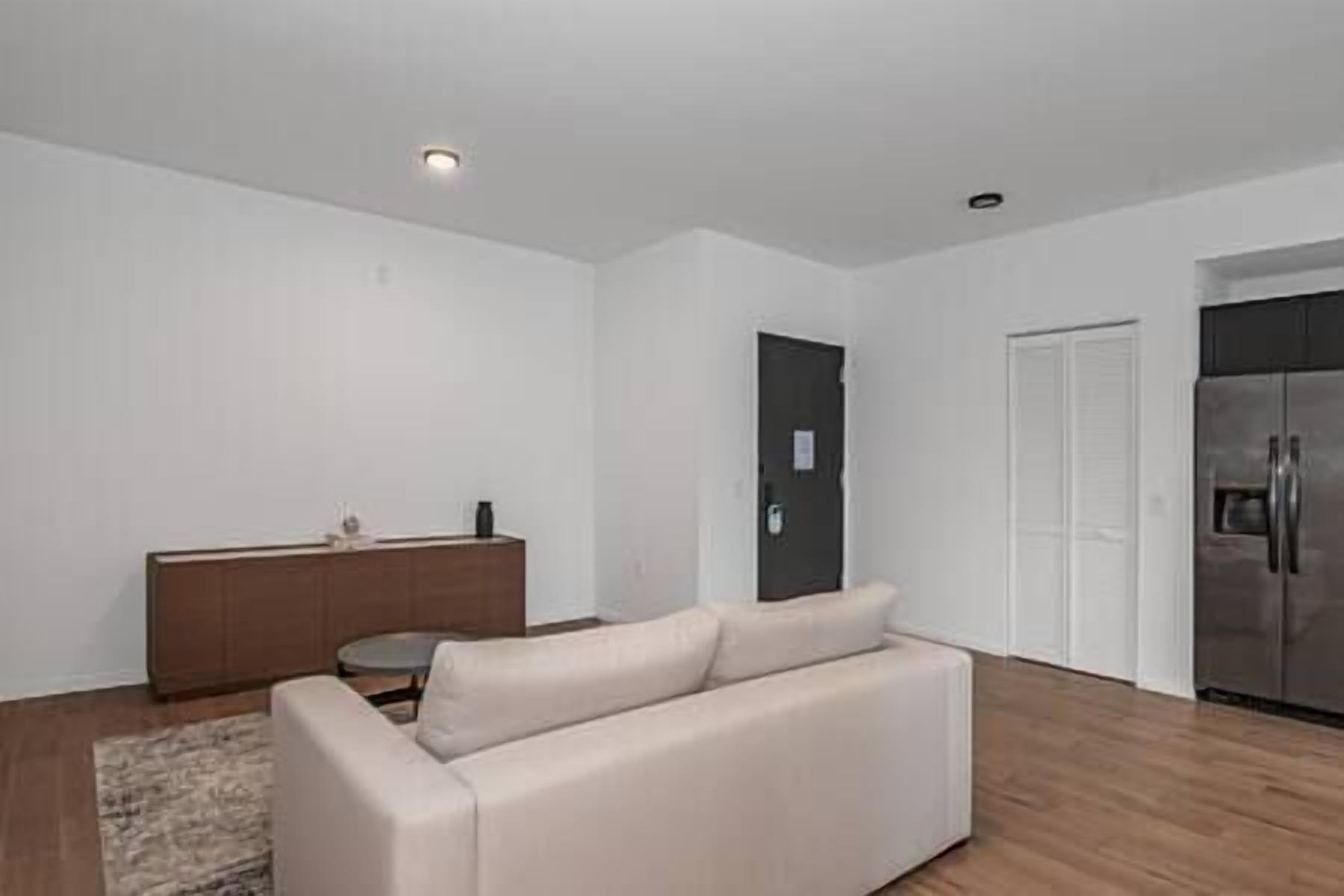 A modern living room with a beige sofa, a small round table, and a dark-colored cabinet.