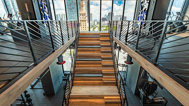 A staircase with a wooden finish, metal railings, and gym equipment on either side. - Cozy 1 BD Apartment in Downtown #2415 (Miami)
