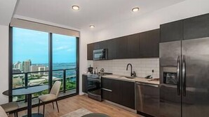 A modern kitchen with a large window, a dining area, and a view of the city. - Modern Lux Studio in Biscayne Boulevard #4008 (Miami)
