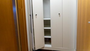 Un couloir étroit, avec des portes blanches donnant sur un placard équipé d’étagères.