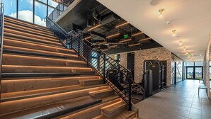 A staircase with wooden steps and metal railings, leading to a fitness area with exercise equipment. - Modern and Spacious Studio in Downtown #2207 (Miami)