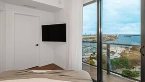 A modern bedroom with a large window offering a view of a coastal area.