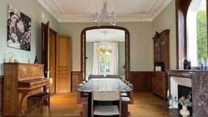 Comedor con una mesa de mármol, sillas de madera, un candelabro y una vista a través de un arco.