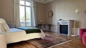 Un dormitorio con cama, chimenea, alfombra y una silla.