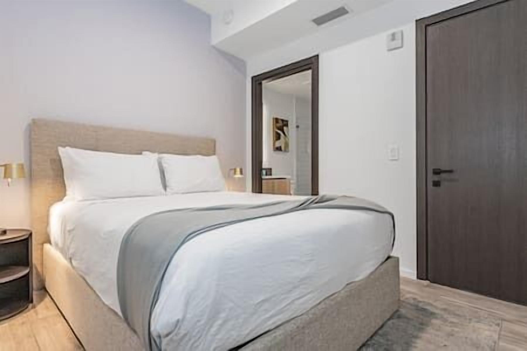 Une chambre à coucher comprenant un lit, des tables de chevet, une armoire et un miroir.