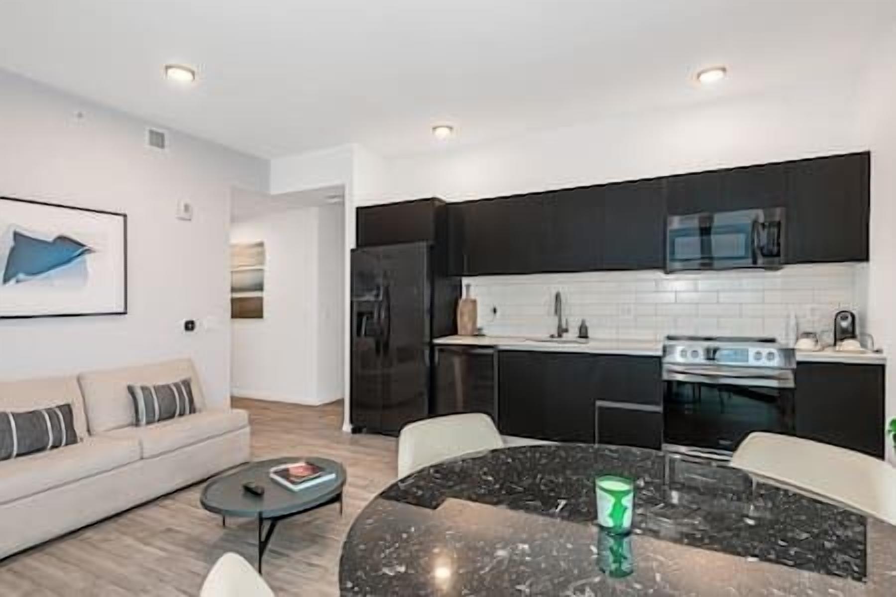 A modern kitchen with dark cabinets, a white countertop, and a built-in oven.