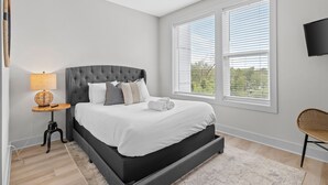 A modern bedroom with a large bed, a bedside table with a lamp, and a chair.