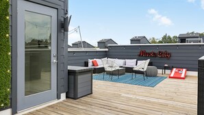 A rooftop patio with a seating area, a small table, and a sign that reads "Music City".