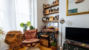 Un salón acogedor con un sillón de cuero, estanterías de madera, un espejo grande y un televisor.