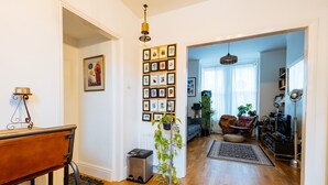 Un salón espacioso con suelo de madera, un sofá gris, una mesa de centro y un ventanal con cortinas de encaje.