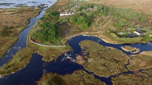 An aerial view of a coastal area with a river, a bridge, and a small settlement with houses and greenery. - 8 Bedroom Luxury Country Mansion in Galway (Costelloe)