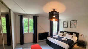 Un dormitorio moderno con una cama grande, un banco rojo, un televisor y una lámpara de techo.
