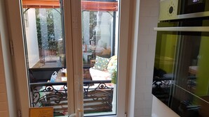 Una stanza con una finestra che si affaccia su un giardino, un tavolino con una sedia e un biglietto sul davanzale.